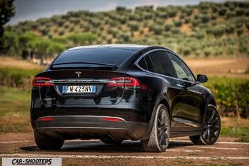 Tesla Model X – rear three-quarter, black against a hillside backdrop