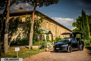 Tesla Model X – front three-quarter, black with doors open in front of a stone building