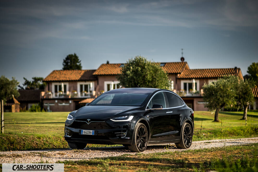 Tesla Model X – front three-quarter, black on a gravel road against a country house