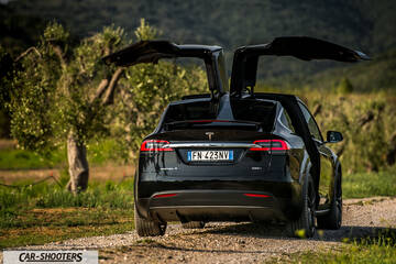 Tesla Model X – rear view, black on a dirt road with gullwing doors open