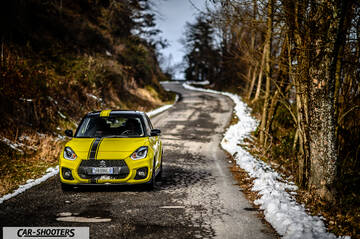 Suzuki Swift Sport – front three-quarter, yellow on a winding snowy road