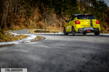 Suzuki Swift Sport – rear three-quarter, yellow on a winding mountain road