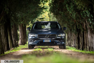 Volvo V60 – front three-quarter, dark blue on a dirt road between trees