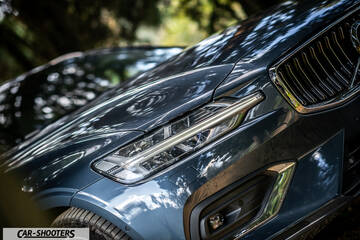 Volvo V60 – front three-quarter, dark blue metallic parked outdoors near trees