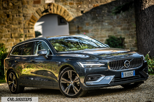 Volvo V60 – front three-quarter, dark grey metallic against a stone archway