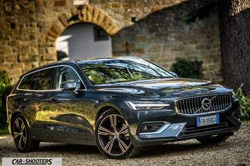 Volvo V60 – front three-quarter, dark grey metallic against a stone archway