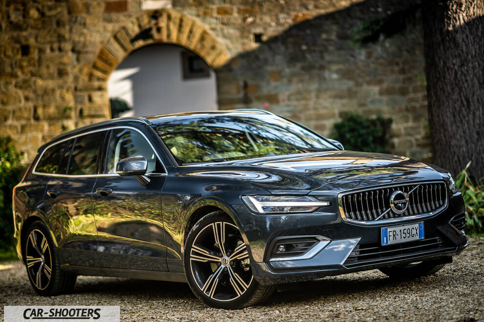 Volvo V60 – front three-quarter, dark grey metallic against a stone archway