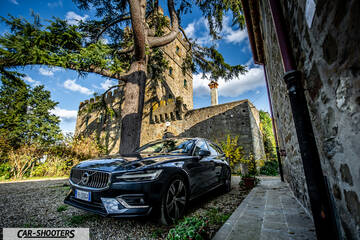 Volvo V60 – front three-quarter, dark blue against an old castle backdrop