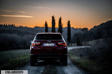 Jeep Compass – rear view, dark red on a dirt road at sunset