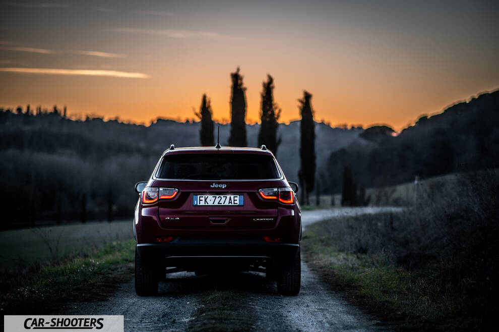 Jeep Compass – rear view, dark red on a dirt road at sunset