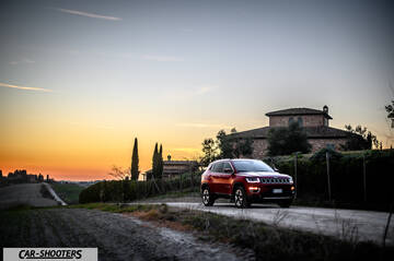 Jeep Compass – front three-quarter, red on a country road at sunset