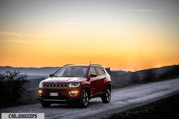 Jeep Compass – front three-quarter, red on a dirt road at sunset
