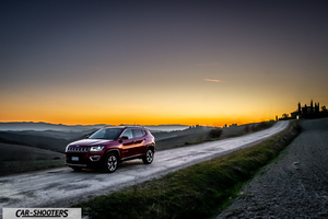 Jeep Compass – front three-quarter, dark red on a country road