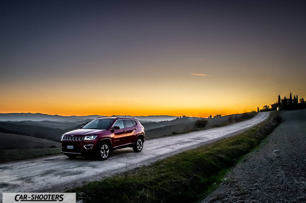 Jeep Compass – front three-quarter, dark red on a country road