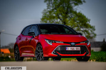 Toyota Corolla Hybrid – front three-quarter, red against a blurred green background