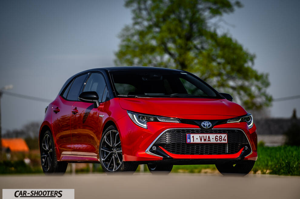 Toyota Corolla Hybrid – front three-quarter, red against a blurred green background