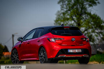 Toyota Corolla Hybrid – rear three-quarter, red metallic on an asphalt road
