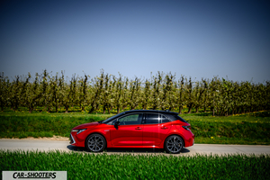 Toyota Corolla Hybrid – side profile, red metallic on a country road