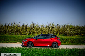 Toyota Corolla Hybrid – side profile, red metallic on a country road
