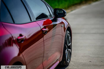 Toyota Corolla Hybrid – side profile, red metallic on a paved road
