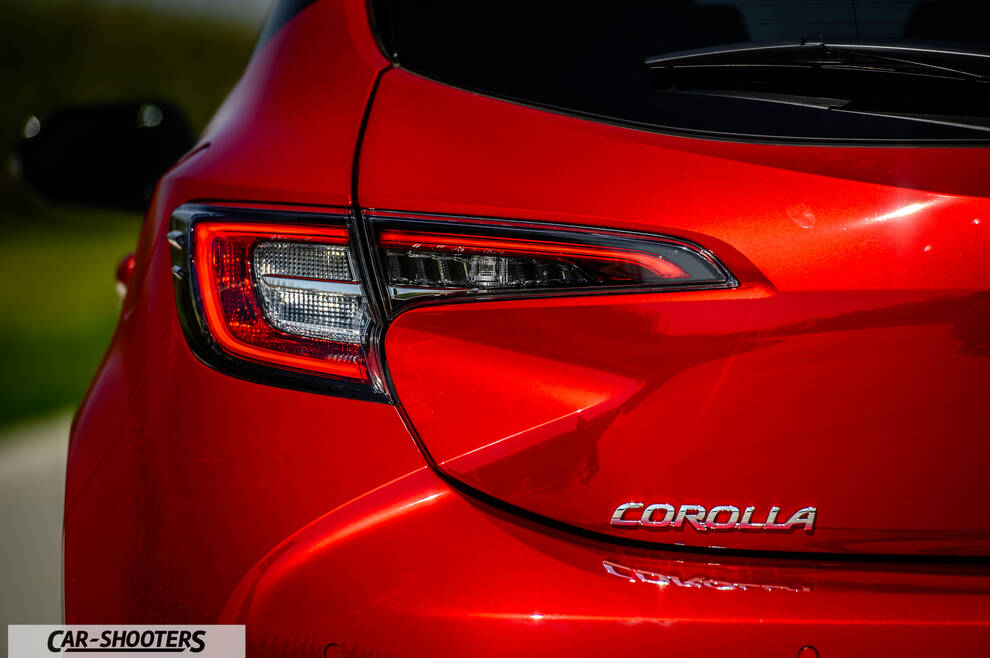 Toyota Corolla Hybrid – rear view, bright red against an outdoor backdrop