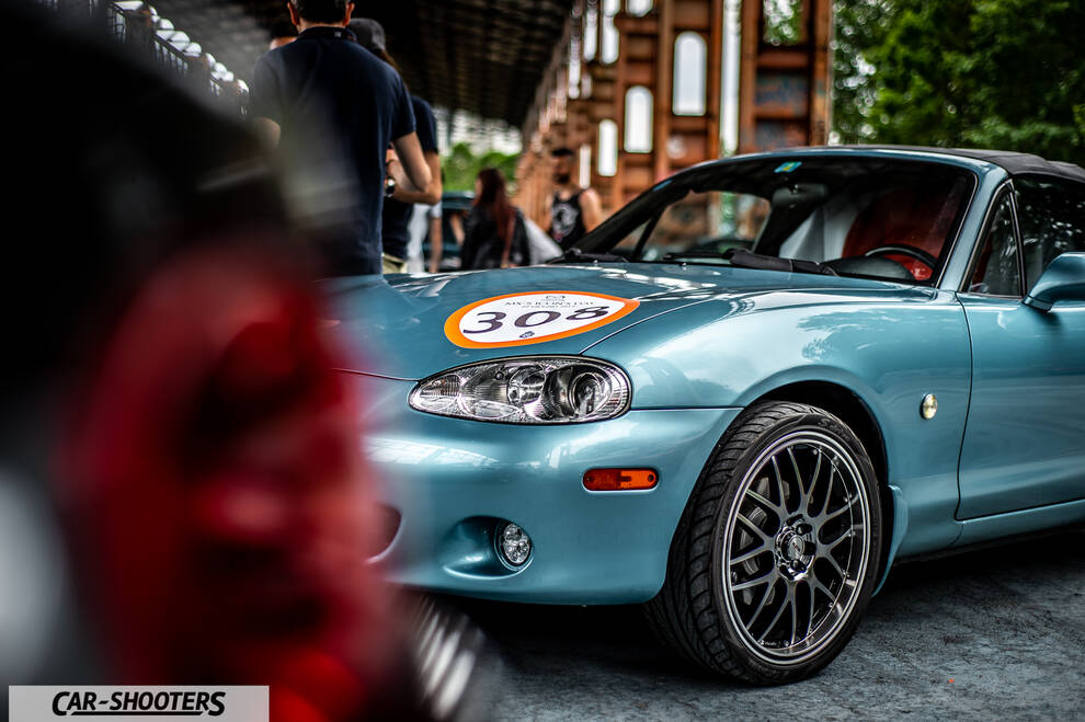 front three-quarter, light blue metallic at a car event