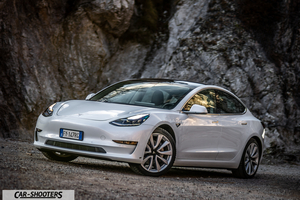 Tesla Model 3 – front three-quarter, white against a rocky mountain backdrop