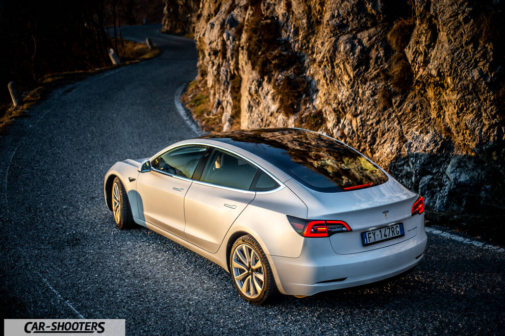 Tesla Model 3 – rear three-quarter, white on a winding mountain road