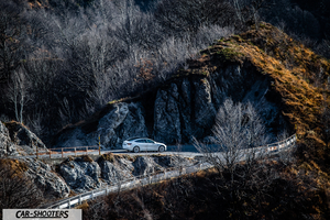 Tesla Model 3 – rear three-quarter, white against a mountain backdrop