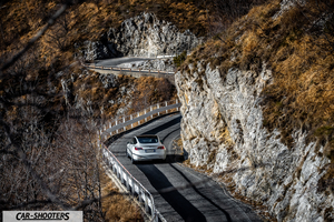 Tesla Model 3 – rear view, white on a winding mountain road