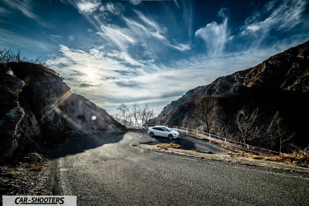 Tesla Model 3 – front three-quarter, white on a winding mountain road
