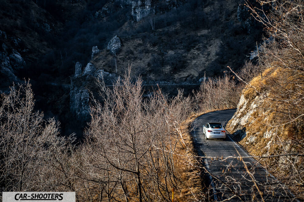 Tesla Model 3 – rear view, white on a winding mountain road