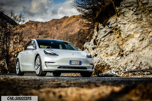 Tesla Model 3 – front three-quarter, white against a mountain backdrop