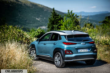 Hyundai Kona electric – rear three-quarter, blue against a mountain backdrop