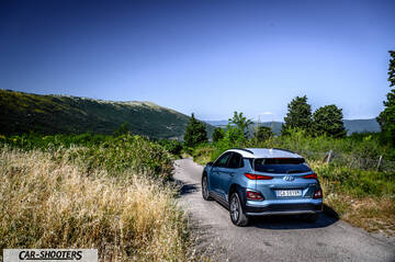 Hyundai Kona electric – rear three-quarter, blue metallic on a country road