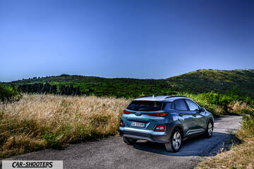 Hyundai Kona electric – rear three-quarter, light blue on a country road
