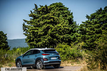 Hyundai Kona electric – rear three-quarter, blue on a country road