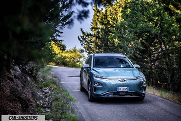 Hyundai Kona electric – front three-quarter, light blue on a winding road