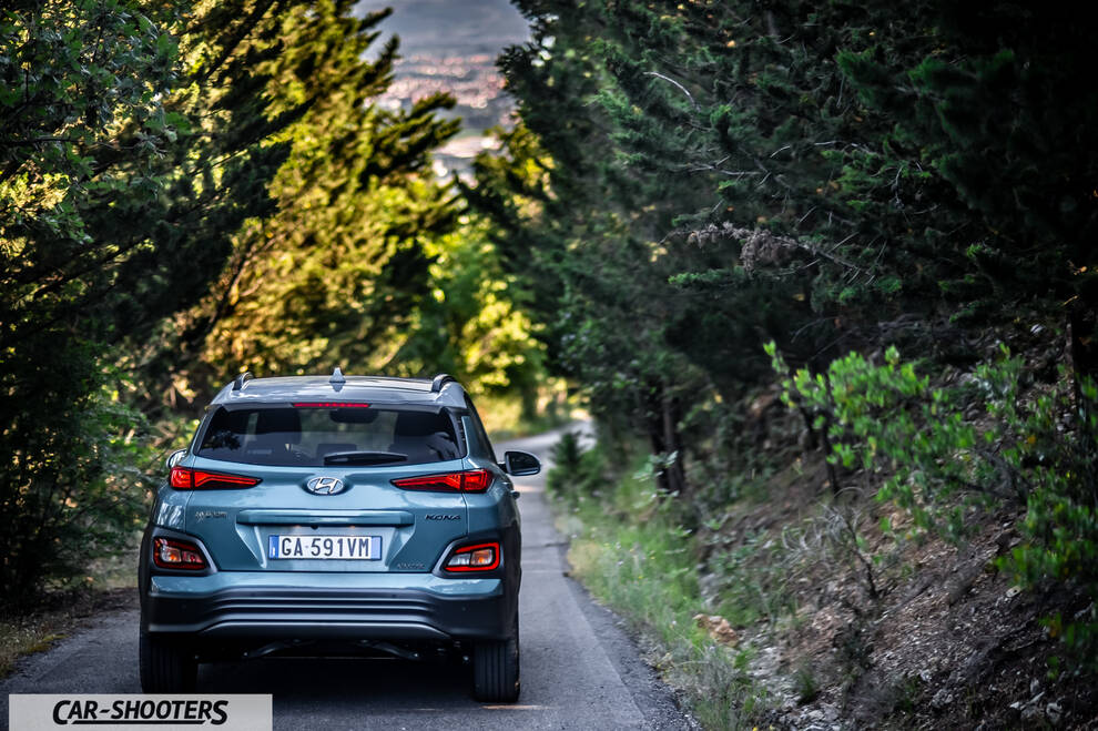 Hyundai Kona electric – rear view, teal blue on a tree lined road