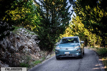 Hyundai Kona electric – front three-quarter, light blue on a winding road