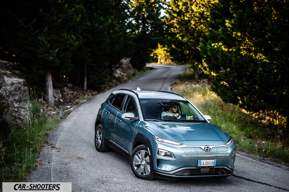 Hyundai Kona electric – front three-quarter, light blue on a winding road