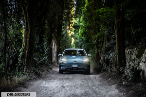 Hyundai Kona electric – front three-quarter, grey metallic on a country road