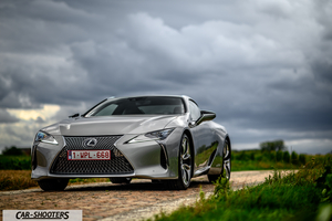 Lexus LC500h – front three-quarter, silver on a dirt road under a cloudy sky