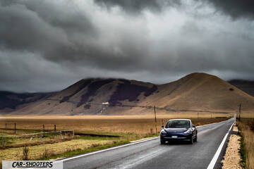 Tesla Model S Performance – front three-quarter, dark blue on a road against a mountain backdrop