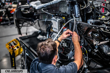 Dallara – engine bay, mechanic working on exposed mechanical parts