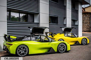 Dallara – rear three-quarter, yellow parked in front of a modern building