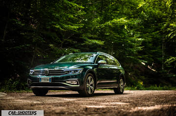 Volkswagen Passat Alltrack – front three-quarter, dark green metallic on a dirt road in a forest