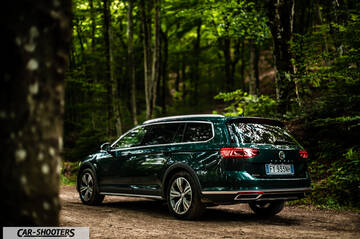 Volkswagen Passat Alltrack – rear three-quarter, dark green metallic on a forest road
