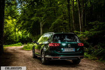 Volkswagen Passat Alltrack – rear three-quarter, dark green on a dirt road in the forest