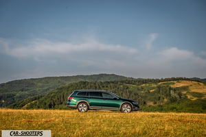 Volkswagen Passat Alltrack – side profile, green metallic against a mountain backdrop